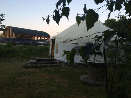 a white tent in a field with a building in the background at Inch Hideaway Eco Camping in Whitegate