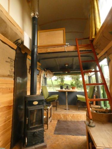 a tiny house with a fireplace and a bunk bed at Inch Hideaway Eco Camping in Whitegate