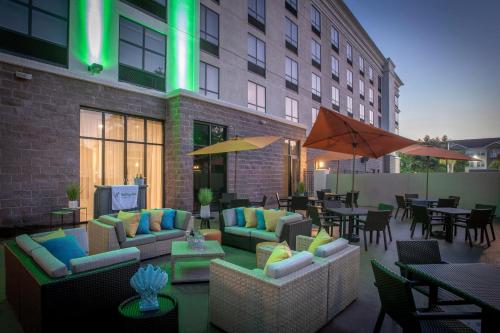 an outdoor patio with couches and tables and chairs at Holiday Inn Pensacola - University Area by IHG in Pensacola