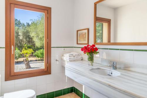 a white bathroom with a sink and a window at Finca Son Blat in Porto Cristo