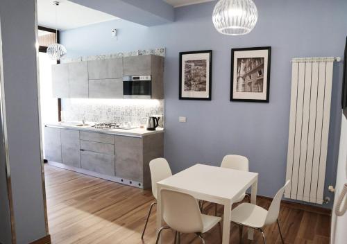 una cucina e una sala da pranzo con tavolo e sedie bianchi di Residenza La Reggia a Caserta