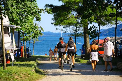 a group of people riding bikes down a path near the water at Campeggio Conca D'Oro in Baveno
