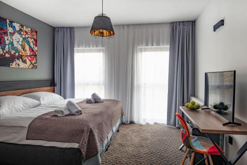 a bedroom with a bed and a desk and windows at Hotel Mamut in Poprad