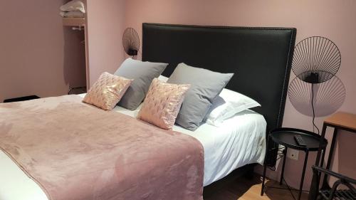 a bedroom with a large bed with pillows and a fan at Le Beaugency in Beaugency