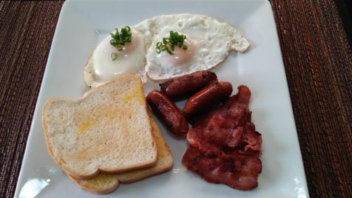 un piatto di prodotti per la colazione con uova, pancetta e pane tostato di Hidden Jewel Resort a Panglao