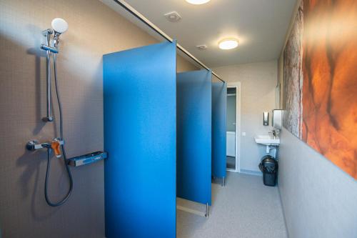 uma casa de banho com uma cabina de duche azul e um lavatório. em Hostel Sili em Mežciems