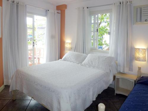 a bedroom with a white bed and two windows at Pousada Casablanca in Abraão