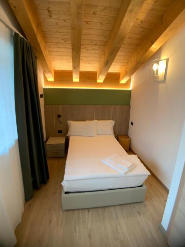 a bed in a small room with a wooden ceiling at Appartamenti Passuello Padola - Verde in Padola
