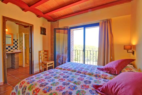a bedroom with a bed and a large window at Mas Del Cigarrer Allotjament Rural in Horta de San Joan