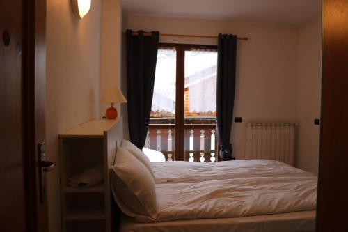 a bedroom with a bed and a window with a balcony at Residence Weissthor in Macugnaga