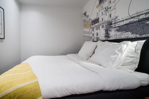 łóżko z białą pościelą i poduszkami w pokoju w obiekcie SUITE DESNOS : au cœur de la Rive Gauche, neuf, design, 2 personnes w Paryżu