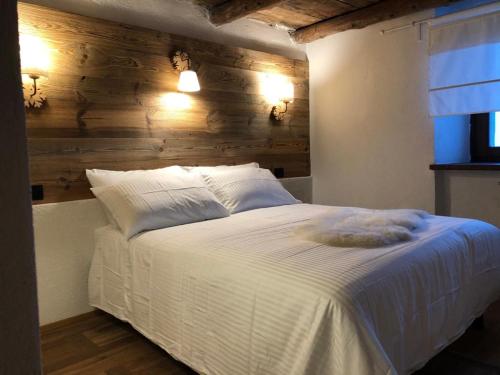 1 dormitorio con cama blanca y pared de madera en Chalet Morge, en La Salle