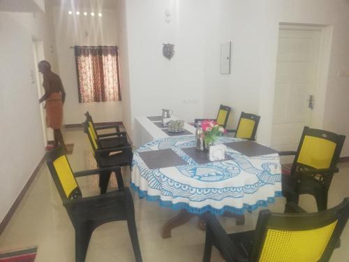 a dining room with a table and yellow chairs at Takashi Homestay North Paravur Near Muziris in North Paravur