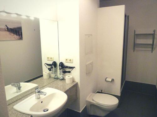 a bathroom with a sink and a toilet and a mirror at Ferienwohnung Beach Loft im Haus Kühlung in Kühlungsborn