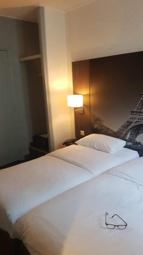 a pair of white beds in a hotel room at Hotel Victoria in Paris