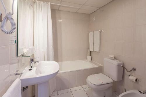 a white bathroom with a toilet and a sink at Best Western Hotel Dom Bernardo in Faro