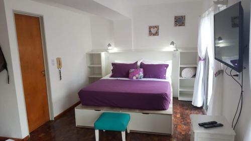 a bedroom with a purple bed and a blue chair at Luminoso Depto con terraza propia y en la mejor ubicación in Córdoba