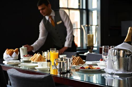 un hombre parado frente a una mesa con comida en Grosvenor House Suites, en Londres