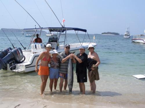 a group of people standing on the beach near a boat at Casa del Sol Bed and Breakfast in Contadora