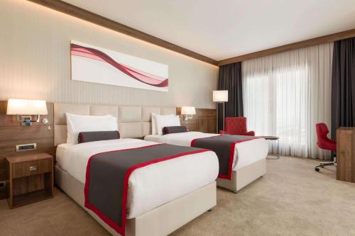 a hotel room with two beds and a desk at Ramada by Wyndham Beylikduzu in Istanbul