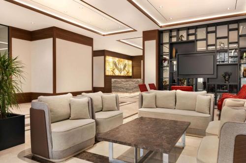 a lobby with chairs and a table and a tv at Ramada by Wyndham Beylikduzu in Istanbul
