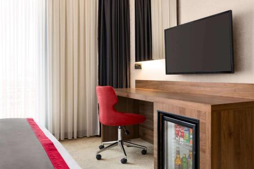 a room with a desk with a television and a red chair at Ramada by Wyndham Beylikduzu in Istanbul