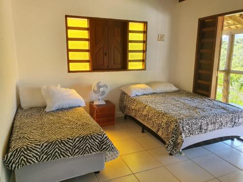 two beds in a room with a mirror and a window at Casa da Rua 1 - Cavalcante/GO in Cavalcante