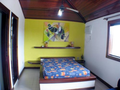 1 dormitorio con cama y pared amarilla en Geriba, casa de 4 qts charmosa com ar, DISPONIVEL CARNAVAL en Búzios