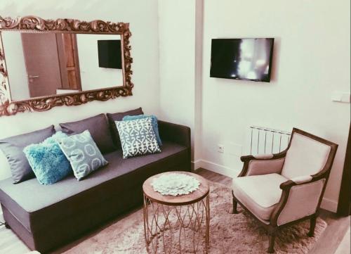 a living room with a couch and a mirror and a chair at La Fuentona de Santillana in Vispieres