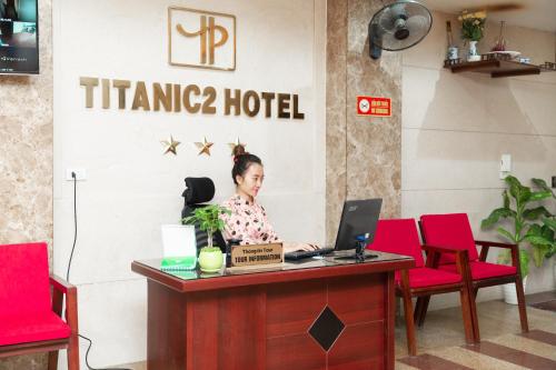 a woman sitting at a desk with a laptop at Titanic 2 Hotel in Hanoi