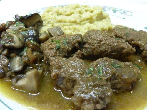 a plate of food with meat and mushrooms and bread at Albergo Chalet Lago Antorno in Misurina