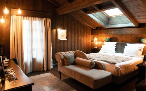a bedroom with a bed and a chair and a window at Hotel Le Castel in Chamonix-Mont-Blanc