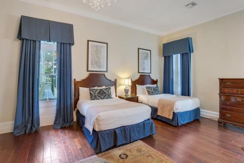 a bedroom with two beds with blue curtains at Andrew Jackson Hotel French Quarter in New Orleans