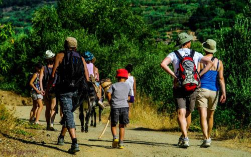grupa ludzi idących po polnej drodze z końmi w obiekcie Enagron Ecotourism Village w mieście Axós