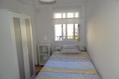 Łóżko w małym pokoju z oknem w obiekcie Bueno, bonito y barato w Maladze