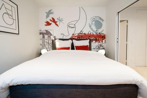 une chambre avec un grand lit blanc avec des oreillers rouges dans l'établissement SUITE COCTEAU : au cœur de la Rive Gauche, neuf, design, 2/4/6 personnes, à Paris