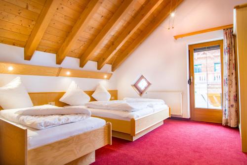 two beds in a room with a red carpet at Apart Bergblick in Ischgl
