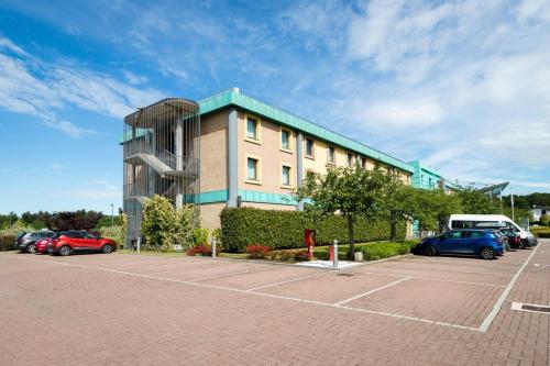 a building with cars parked in a parking lot at Crowne Plaza Milan - Malpensa Airport by IHG in Case Nuove