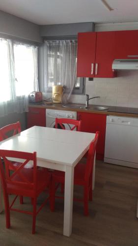 une cuisine avec des placards rouges, une table blanche et des chaises dans l'établissement EA115 - 2 Pièces 6 Pers proche centre des Carroz, aux Carroz d'Arâches