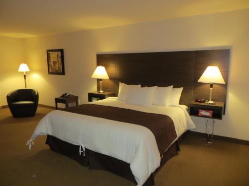 a hotel room with a large bed and a chair at Villegiature Deux Rivieres Resort in Tracadie