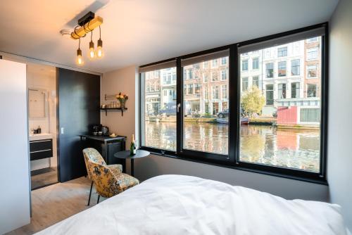 アムステルダムにある2 Houseboat Suites Amsterdam Prinsengrachtの運河の景色を望む大きな窓付きのベッドルーム1室