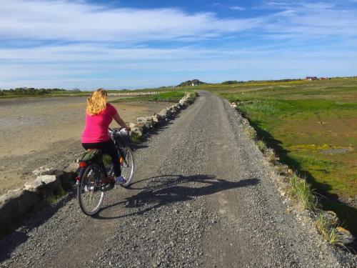 a woman riding a bike down a dirt road at Orcas View Vestresand Lofoten in Bøstad