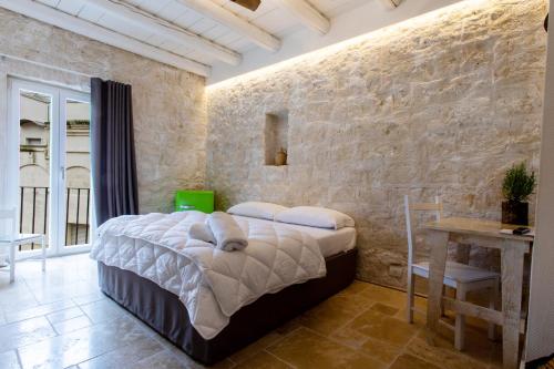 una camera con letto e parete in pietra di B&B PIAZZA SAN GIOVANNI - ESSENZE DELLA MURGIA ad Altamura