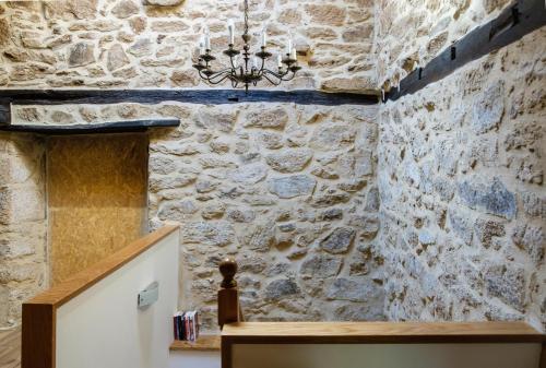 a room with a stone wall and a chandelier at Casa do Comediante in Cerdeira