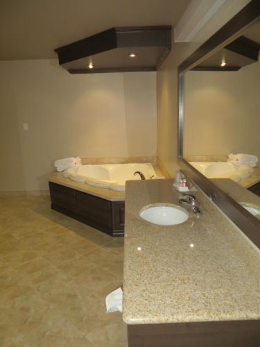a bathroom with a sink and a tub and a mirror at Villegiature Deux Rivieres Resort in Tracadie