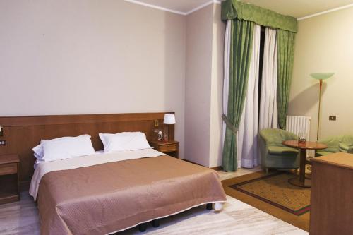 サリーチェ・テルメにあるHotel Clementiのベッドと椅子付きのホテルルーム