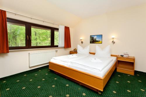 ein Schlafzimmer mit einem großen Bett mit weißer Bettwäsche in der Unterkunft Restaurant & Hotel Baumhaus Hagen in Sassnitz