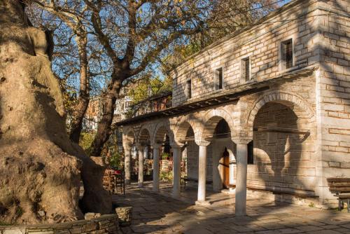 an old stone building with trees in front of it at Charis Guesthouse in Makrinítsa