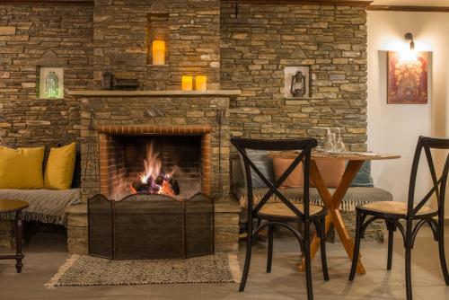 a fireplace in a living room with a table and chairs at Charis Guesthouse in Makrinítsa