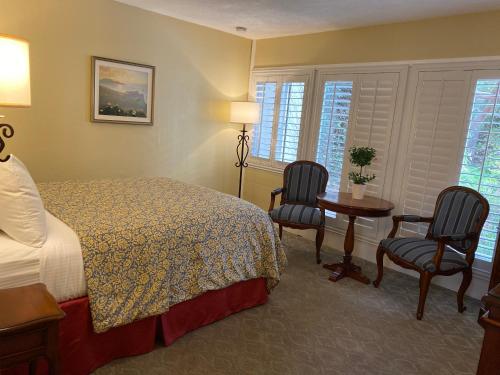 a hotel room with a bed and two chairs and a table at Normandy Inn in Carmel
